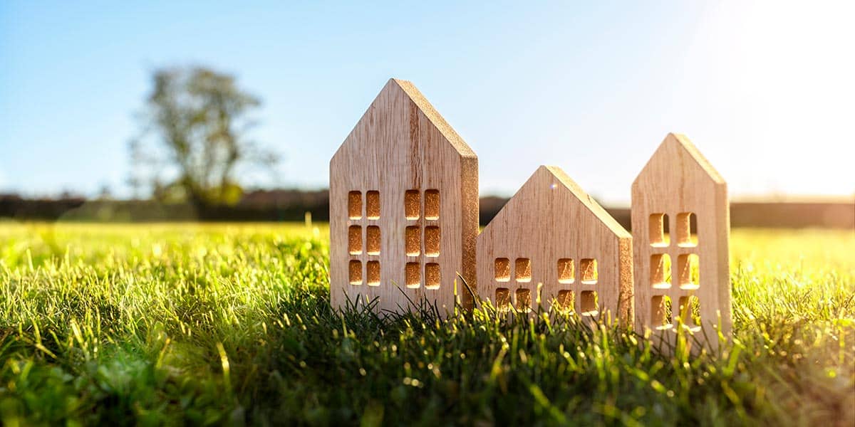 A grassy field with wood carved strucutres that look like little houses.